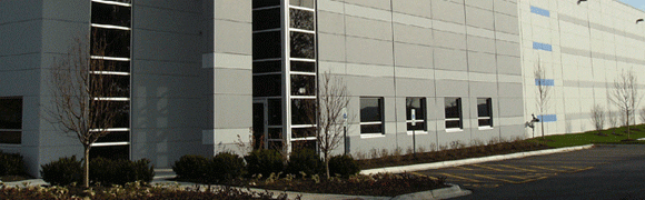 Modern building exterior with large windows and landscaped greenery.