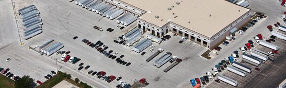 Aerial view of a warehouse with trucks and parked cars.
