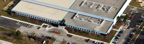 Aerial view of a large building complex with parking and landscaping.