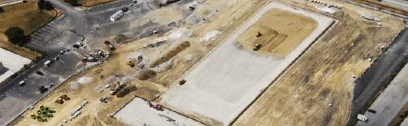 A construction site with earthmoving equipment and groundwork underway.