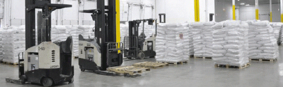 Forklift moving pallet in warehouse.