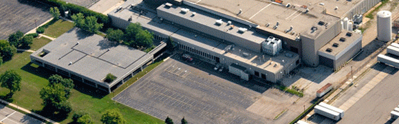 Aerial view of a large commercial warehouse with a loading dock and empty parking lot.
