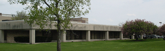 Modern concrete building with large windows and green lawn.