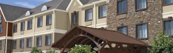 Entrance canopy with wooden beams and stone pillar under a beige building.
