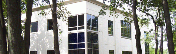 Modern building with large glass windows reflecting trees and sky.