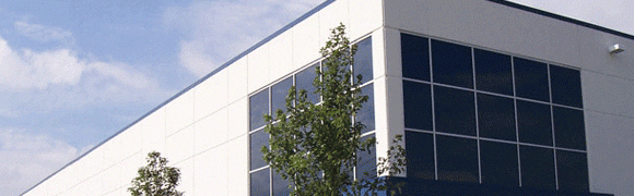 A modern building with reflective windows and a tree in front.
