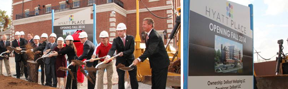 Officials in suits and helmets participate in a groundbreaking ceremony.