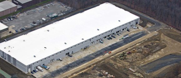 A large industrial warehouse with multiple loading docks and trucks parked outside.