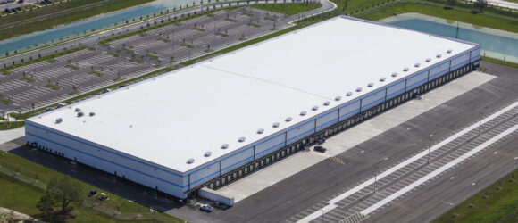 Large warehouse with parking lot aerial view.