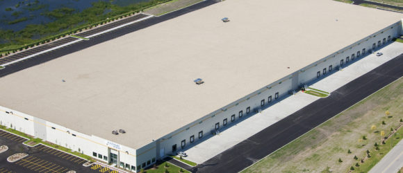 A large industrial warehouse with multiple loading docks and trucks.