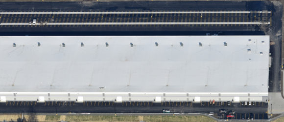 Aerial view of a large industrial warehouse with solar panels on the roof.
