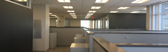 Empty office with cubicles and fluorescent lighting.