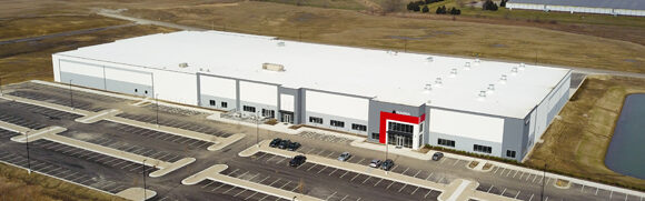 Large industrial warehouse building with parking lot.