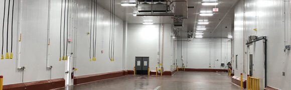 Large, empty industrial warehouse interior with lights.