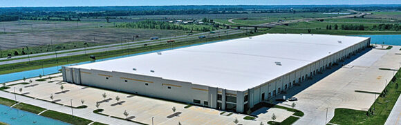 Large warehouse building with surrounding landscape.