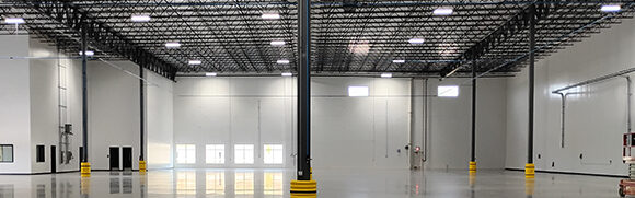 Empty warehouse interior with high ceiling structure.